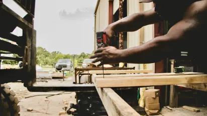 zoom on man's hands screwing into planks 